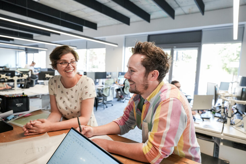 Two member of the architectural team discussing site layout in an open office.