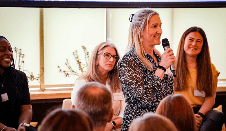 Smiling woman with microphone standing in front of two other women