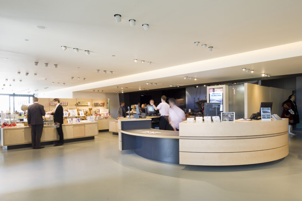 Light reception area with wooden desks and gift shop in the background.