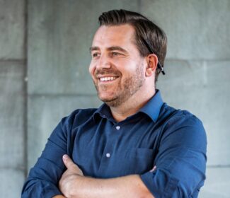 Person with a pencil behind their ear smiling at the camera.
