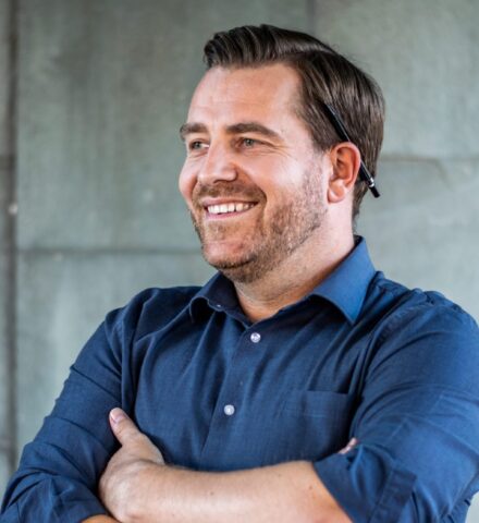 Person with a pencil behind their ear smiling at the camera.