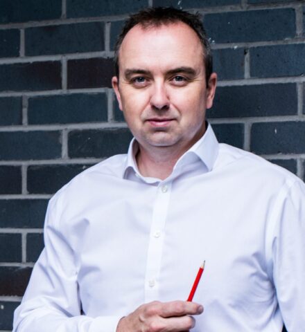 Person holding a pencil smiling at the camera.