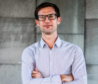 Person holding a pencil smiling at the camera.