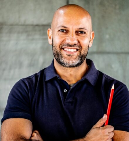 Person holding a pencil smiling at the camera.