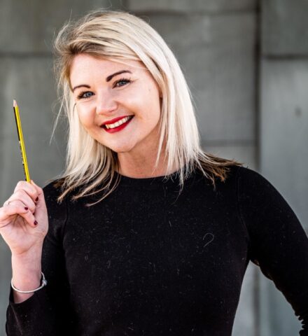 Person holding a pencil smiling at the camera.