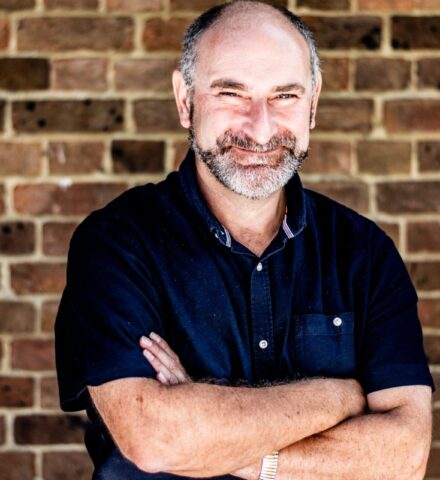 Person holding a pencil smiling at the camera.