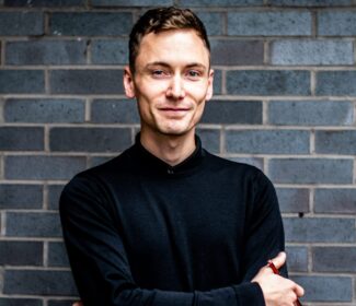 Person holding a pencil smiling at the camera.