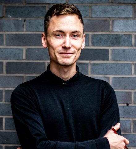 Person holding a pencil smiling at the camera.