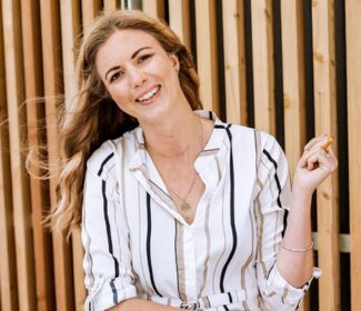 Person holding a pencil smiling at the camera.