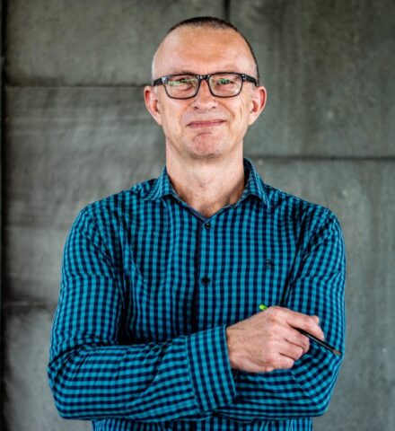 Person holding a pencil smiling at the camera.