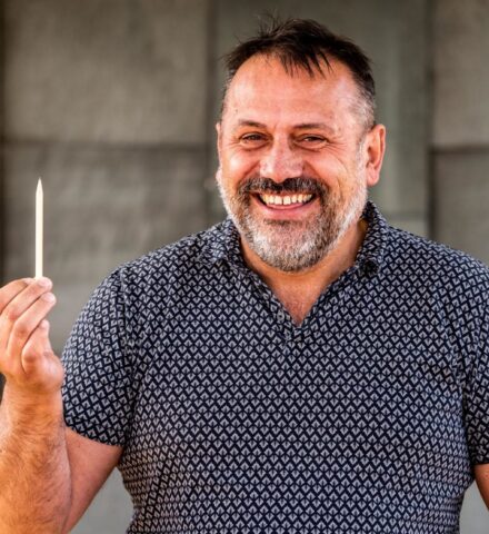 Person holding a pencil smiling at the camera.