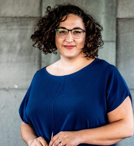 Person holding a pencil smiling at the camera.
