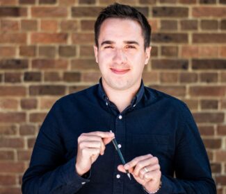 Person holding a pencil smiling at the camera.