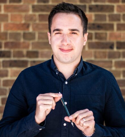 Person holding a pencil smiling at the camera.