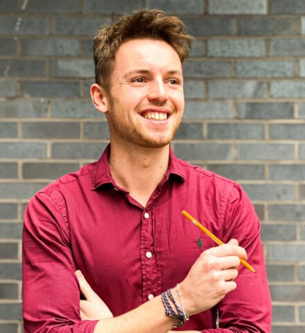 Person holding a pencil smiling at the camera.