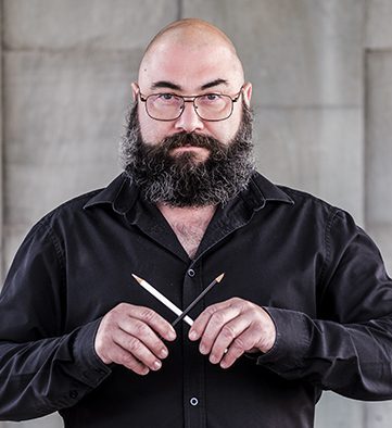 Person holding a pencil smiling at the camera.