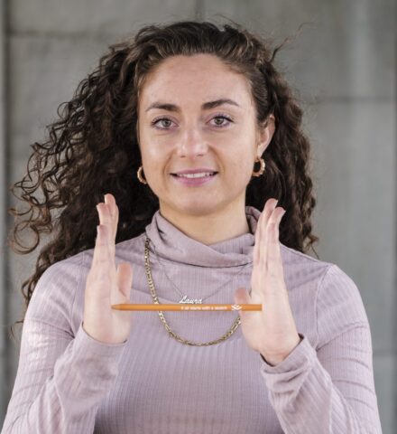Person holding a pencil smiling at the camera.