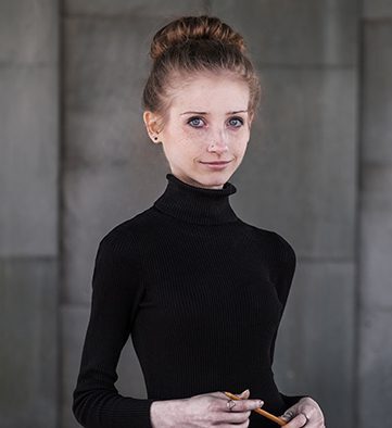 Person holding a pencil smiling at the camera.