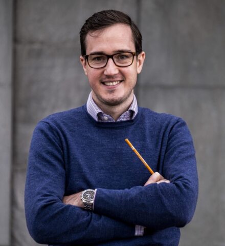 Person holding a pencil smiling at the camera.