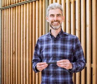 Person holding a pencil smiling at the camera.