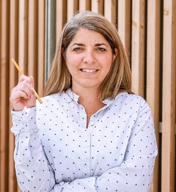 Person holding a pencil smiling at the camera.