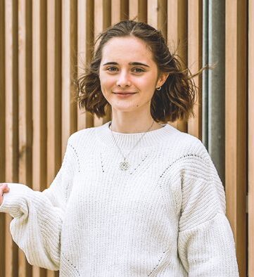 Person holding a pencil smiling at the camera.