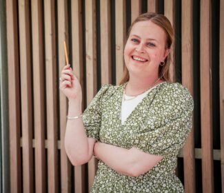Person holding a pencil smiling at the camera.
