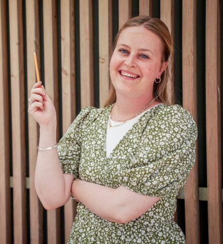 Person holding a pencil smiling at the camera.