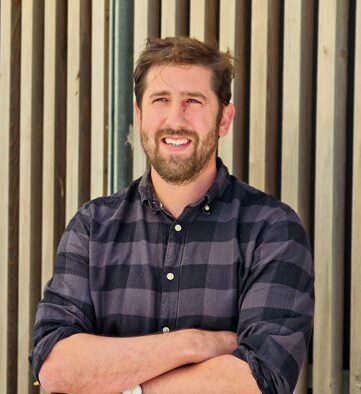 Person holding a pencil smiling at the camera.
