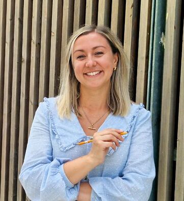 Person holding a pencil smiling at the camera.