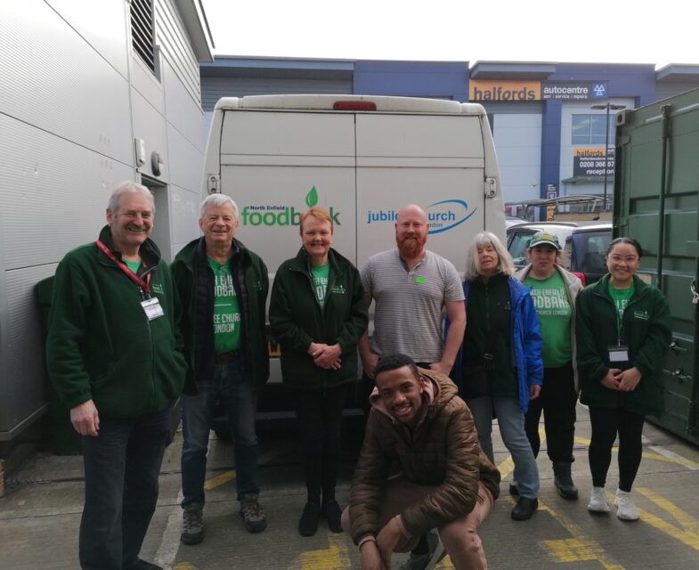 Small group of people standing in front of a white van at a food bank in London.
