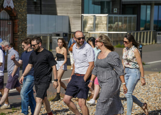Large group of people walking along a path, walking and talking to each other.