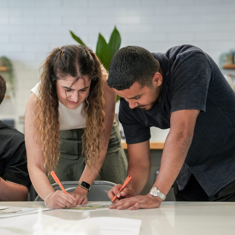 Two architectural assistants looking at a site plan and making adjustments.