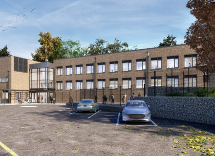 Contemporary brick school building with parking spots in the front and students scattered around the entrance.