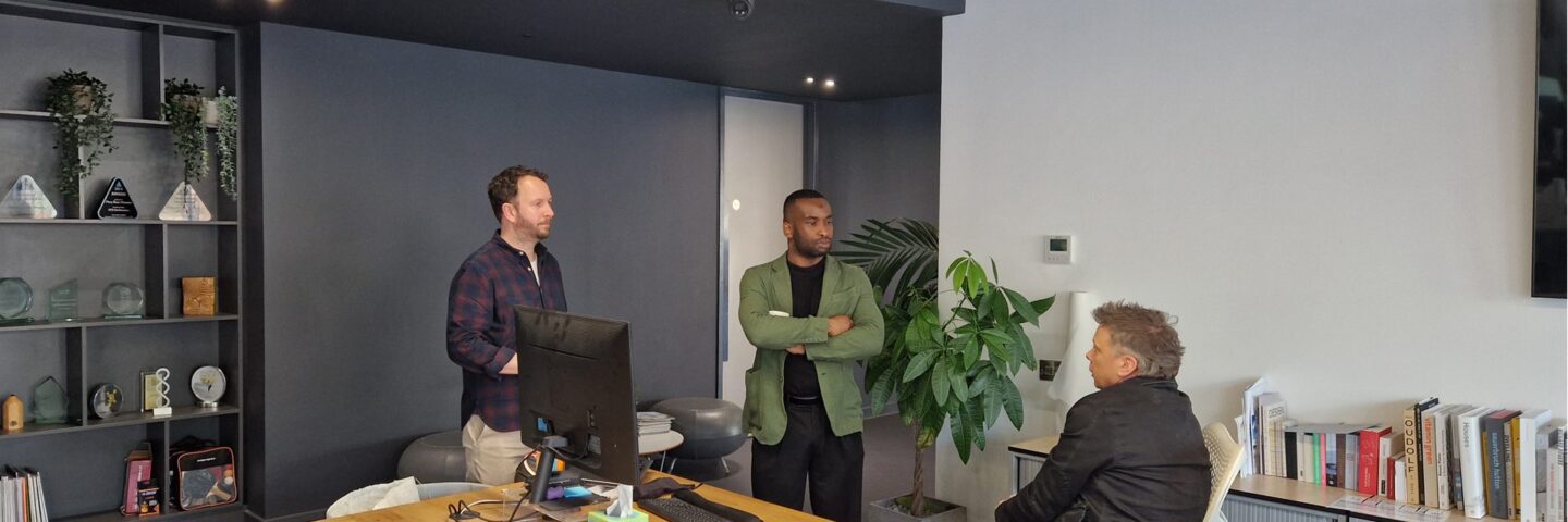 Three people standing in an office having a conversation