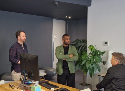 Three people standing in an office having a conversation