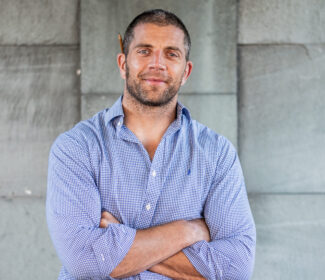 Person with a pencil behind their ear smiling at the camera.