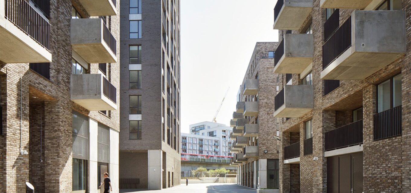 Street between two brick buildings with protruding balconies.