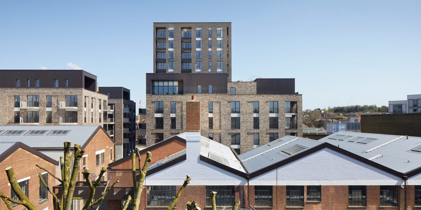 Residential brick tower block with metal cladding details seen over the rooflines of the neighbouring houses.