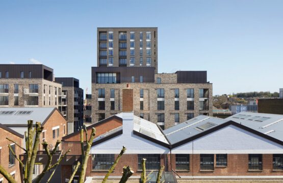 Residential brick tower block with metal cladding details seen over the rooflines of the neighbouring houses.