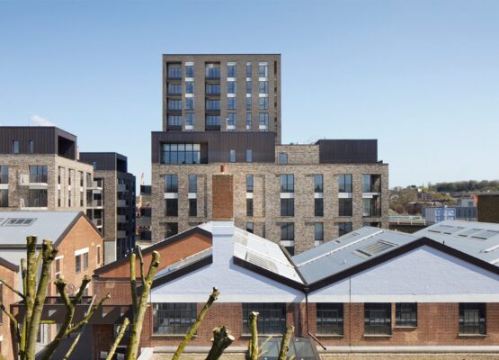 Residential brick tower block with metal cladding details seen over the rooflines of the neighbouring houses.