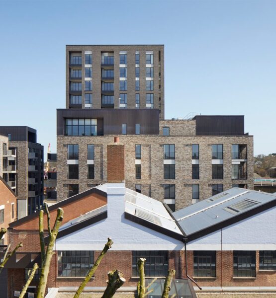 Residential brick tower block with metal cladding details seen over the rooflines of the neighbouring houses.