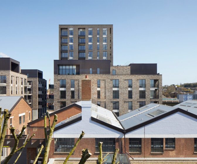 Residential brick tower block with metal cladding details seen over the rooflines of the neighbouring houses.