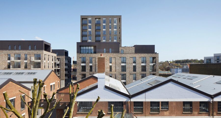 Residential brick tower block with metal cladding details seen over the rooflines of the neighbouring houses.