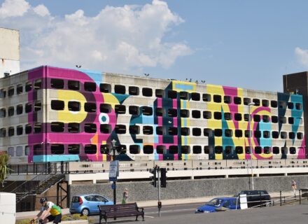 Colourful wall mural on a cinder block multi-storey parking garage.