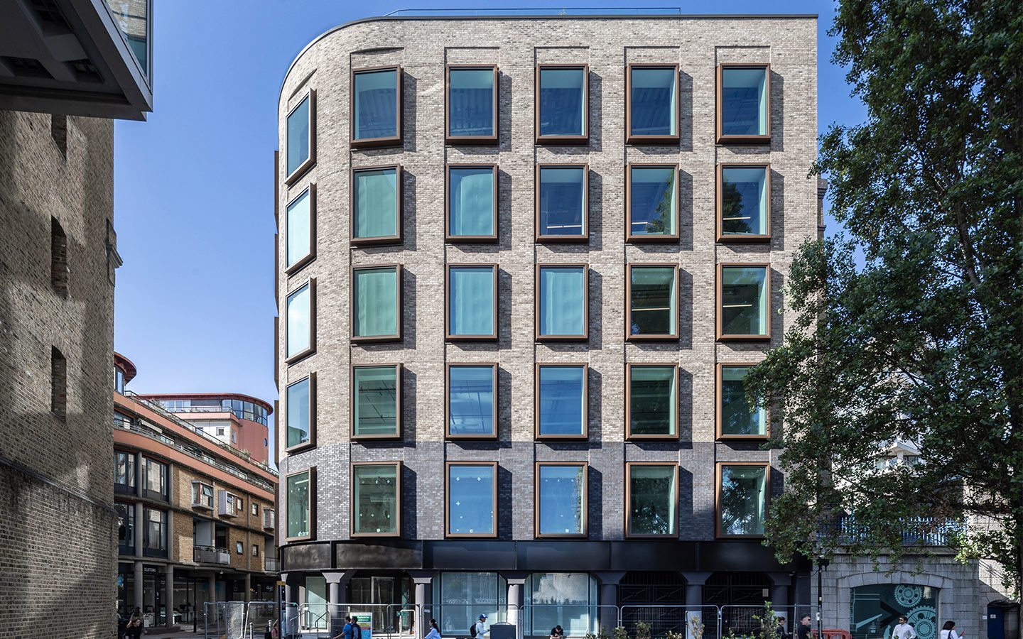 Curved brick building with large windows with metal window frames.