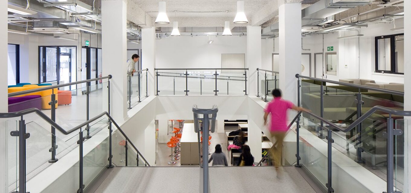 Internal stair case with school children walking down and surrounded by colourful sofas.