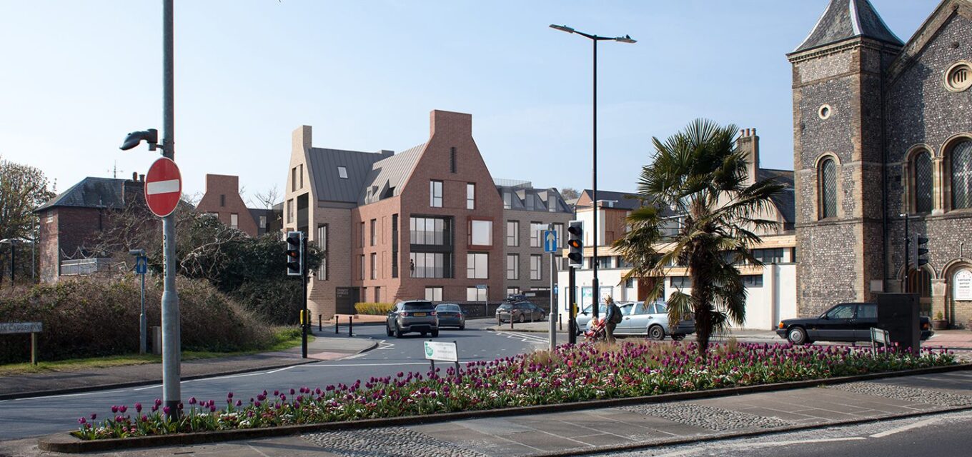 Contemporary residential flatted development with decorative gables next to a flint church and a road.