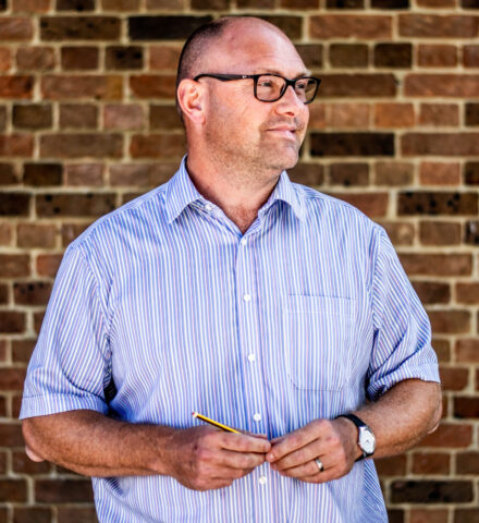 Person holding a pencil smiling at the camera.