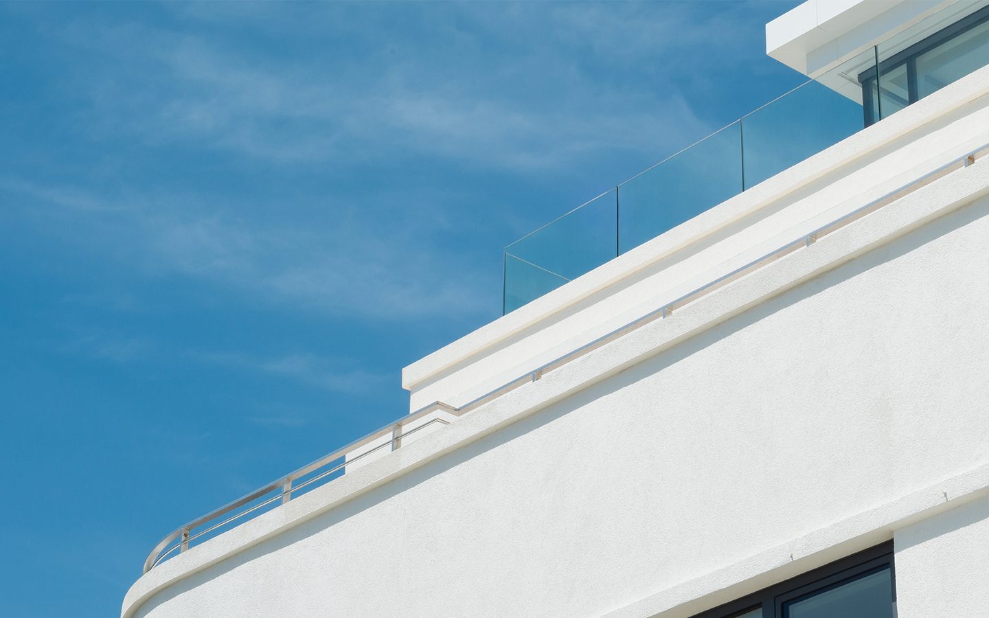 White rendered Art Deco balcony with metal railing and glass balustrade
